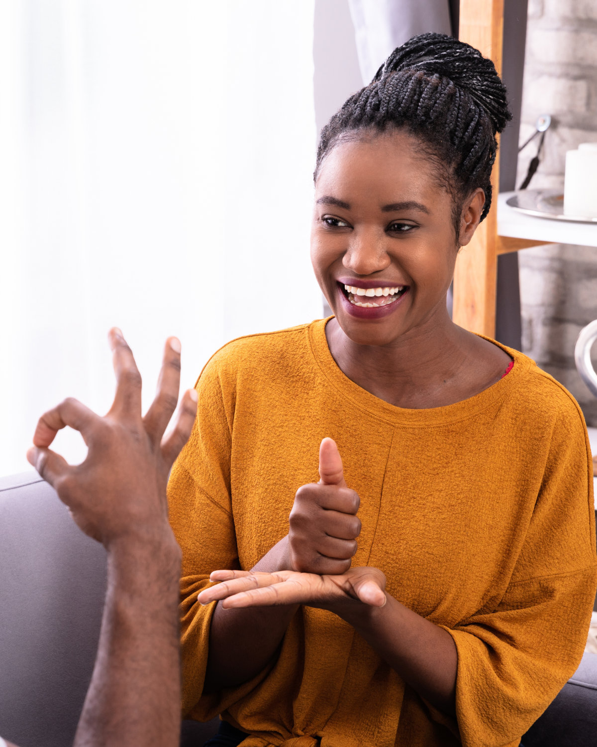 A young woman smiling as she signs in British Sign Language.